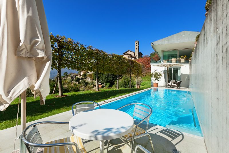 pool deck with outdoor dining table, chairs and an umbrella